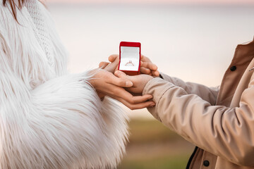 Young couple with engagement ring in box outdoors, closeup