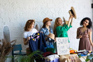 Young women at swap home party - clothes, shoes, bags, jewellery exchange between friends. Zero...