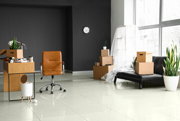 Cardboard boxes with belongings and furniture in interior of office on moving day