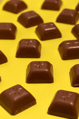 Square pieces of chocolate on a yellow background.