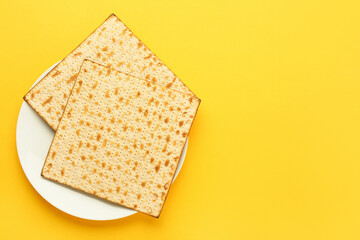 Plate with Jewish flatbread matza for Passover on yellow background