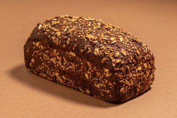 Whole dark bread with seeds on a beige background.
