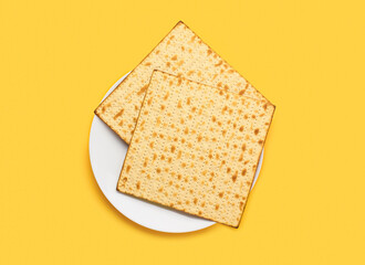 Plate with Jewish flatbread matza for Passover on yellow background