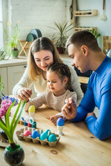 the family paints colorful Easter eggs. mom, dad and daughter celebrate spring holiday together