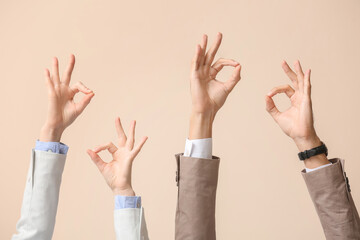 Business workers showing OK on beige background