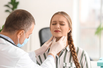Fototapeta premium Doctor examining woman's neck in clinic