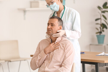 Doctor examining man's neck in clinic
