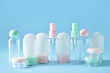 Set of empty travel cosmetic bottles and jars on blue background