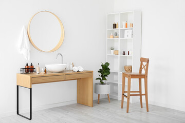 Stylish interior of bathroom with different supplies and modern sink near white wall