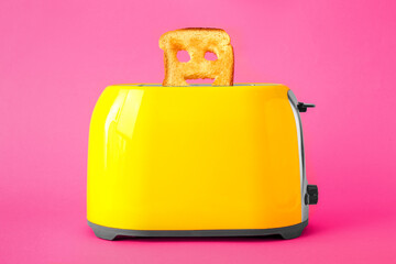 Funny slice of bread in toaster on pink background