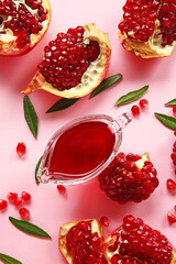 Tasty ripe pomegranate pieces and gravy boat with jam on pink background