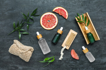 Bottles of grapefruit oil with bathing supplies on dark background