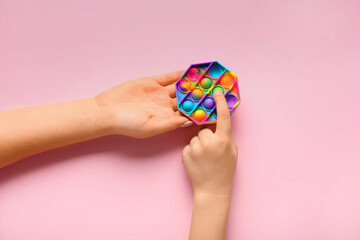 Woman and child with pop it fidget toy on pink background. Concept of autistic disorder