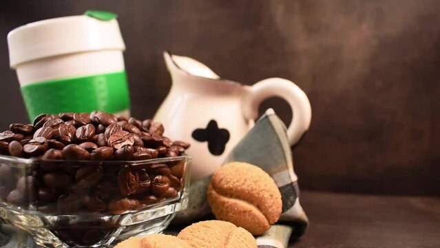 Coffee beans, cookies, milk jug and plastic thermos for hot drinks left by a hand on black table