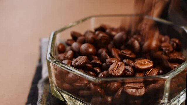 Some black coffee beans falling in a glass pot 