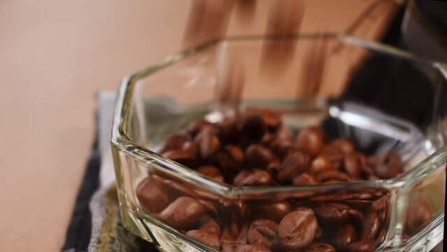 Some black coffee beans going out from a glass pot 