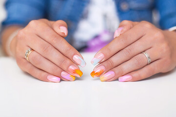 Obraz na płótnie Canvas Beautiful female hands with multicoloured manicure nails, pink, blue and orange gel polish