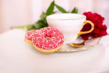 Cup of tea, sweet strawberry donut on golden plate with hydrangea flower