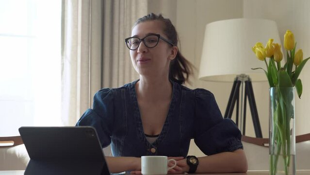 Caucasian Young smiling Woman with glasses waving hello looks at camera Laptop At Home. successful business lady leads conference. Happy Teacher Working On Computer Education, Technology Concept