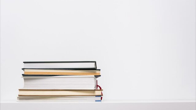 Stop motion animation of growing and shrinking stack of books isolated on white background. Educational or learning concept.