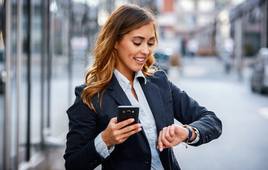 Fototapeta premium Always on time. Businesswoman looking at her watch while waiting a money transfer on the way to office. Business, lifestyle concept