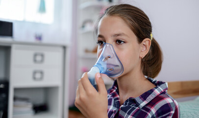 Little girl using inhaler at home. Health care concept