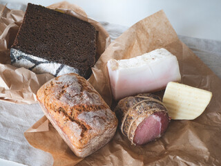 Loaves of rye and wheat sourdough bread, cheese and meat on the table. Concept of fresh farm products, local natural food