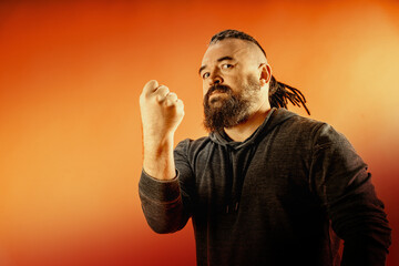 A middle-aged man with a beard and an unusual hairstyle. An adult man with a mohawk and dreadlocks is shaking his fist