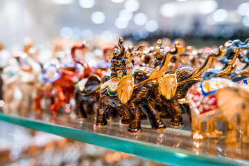 Various colorful elephant figurines display on shelf for sale in shop