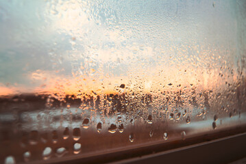 Close-up shot of some raindrops on a window in the sunset.