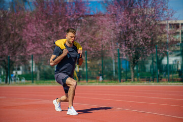 Fototapeta premium Muscular young man exercising with heavy weight bag in the sport stadium. Sporty man working out with heavy weight bag.