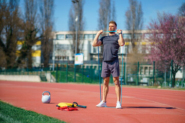 Obraz premium Man with athletic body performs exercises using a resistance band.