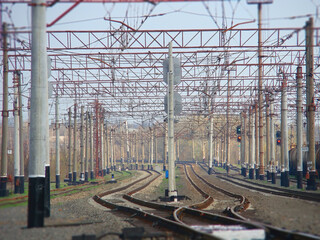 Fototapeta na wymiar The interlacing of the rails at the station surrounded by wires and poles. Industrial landscape background