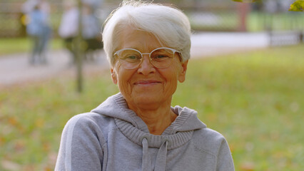 Portrait of elderly Caucasian woman grey hair and glasses in the park selective focus . High quality photo