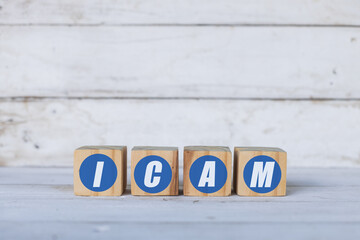 icam concept written on wooden cubes or blocks, on white wooden background.