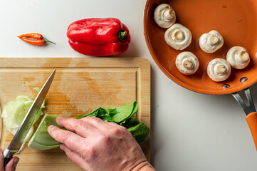 Top view of bok choy chopped on cutting board, peppers and mushrooms on the side