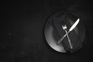 Empty black slate plate on dark stone table. Food background for menu, recipe. Table setting. Flatlay, top view. Mockup for restaurant dish	