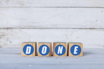 done concept written on wooden cubes or blocks, on white wooden background.
