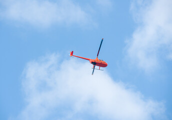 helicopter in the sky on blue sky red orange helicopter flying in summer