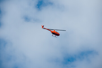 Fototapeta na wymiar helicopter in the sky on blue sky red orange helicopter flying in summer