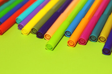 Multi-colored stationery felt-tip pens on a background of multi-colored cardboard paper.