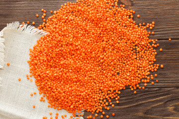 Red lentils scattered on a wooden background.