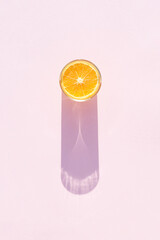 Glass of drink with orange on a pink background. Aesthetic long shadow glass summer concept.
