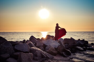 Beautiful seaside landscape with a woman on the beach. Girl in a red dress at the Polish seaside.