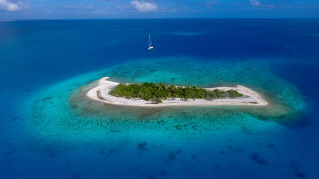 vue a&eacute;rienne bateau dans le lagoon de Rangiroa au mouillage derri&egrave;re un motu de sable blanc 