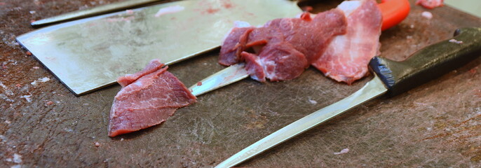 Rohes, frisches Fleisch auf einem Holztisch mit Messern