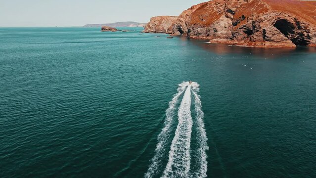 The jet ski runs in the direction of the rock on turquoise water. Aerial view