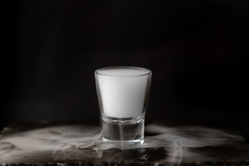 vasito de coctel con reacción química de hielo seco, fondo negro y base de piedra