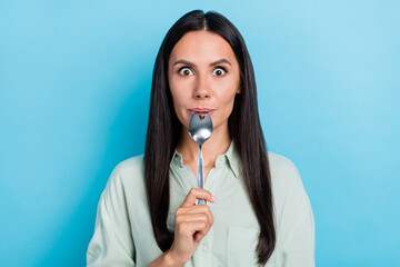 Photo of young pretty lady lick spoon want to eat meal dream dessert isolated over blue color...