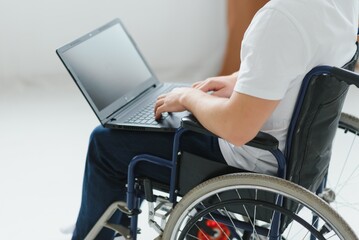 Obraz premium Man in wheelchair working on laptop in living room.